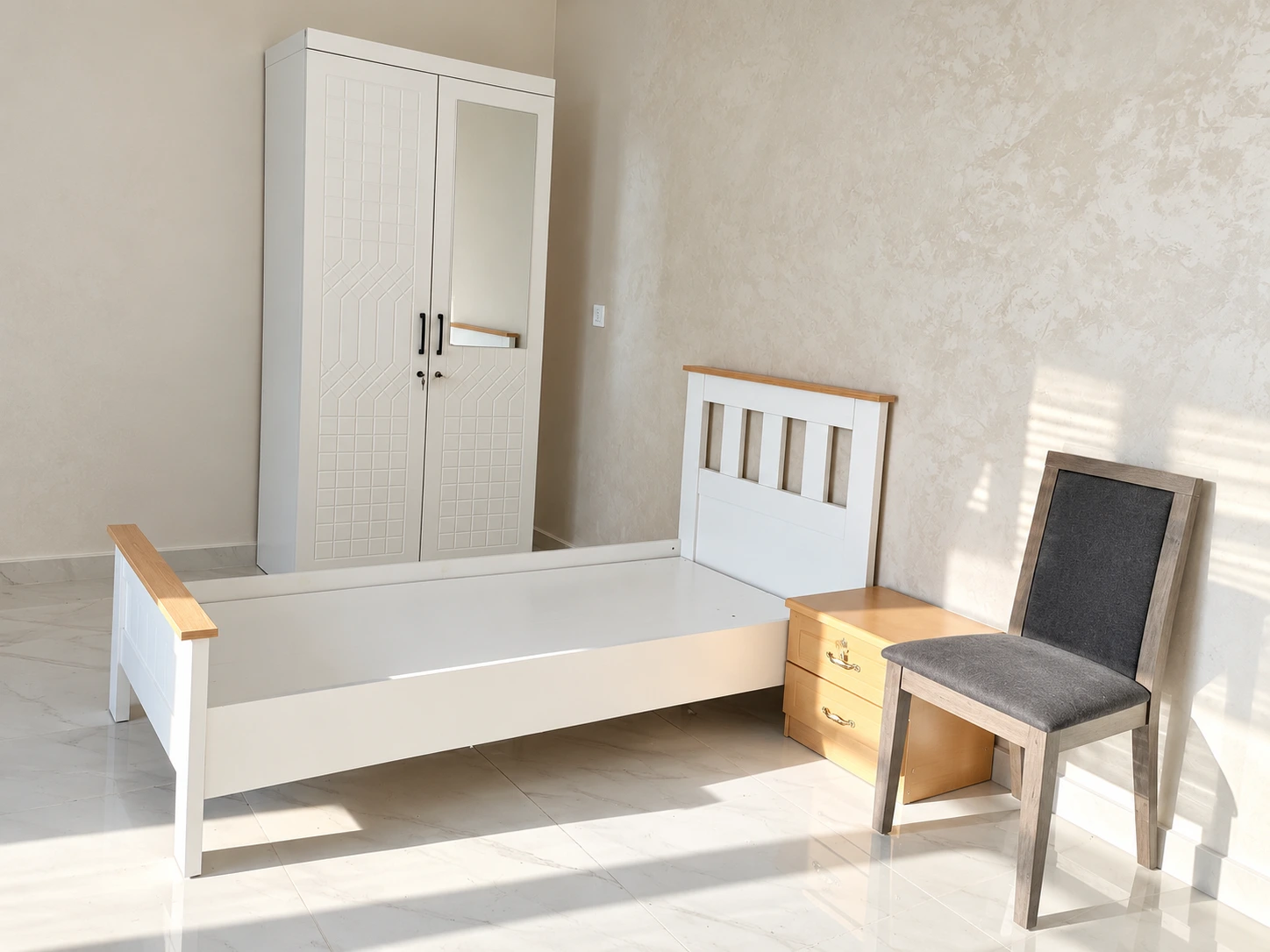 Single bed, mirrored wardrobe, bedside cabinet and chair at Yanqul camp